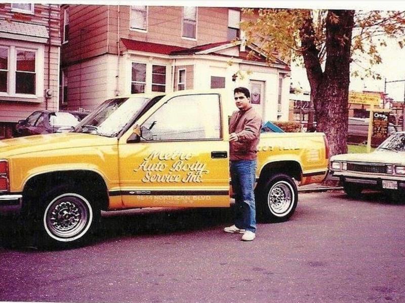 Man standing beside a yellow pickup lettered Metro Auto Body Service Inc., 9614 Northern Blvd
