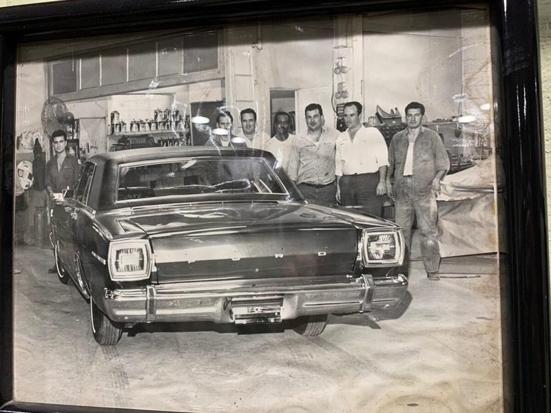 Vintage black-and-white photo of the early Metro Auto Body crew standing behind a Ford inside the shop