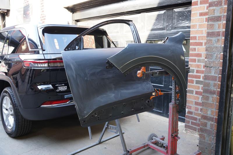 Repainted vehicle panel on a paint stand outside Metro Auto Body