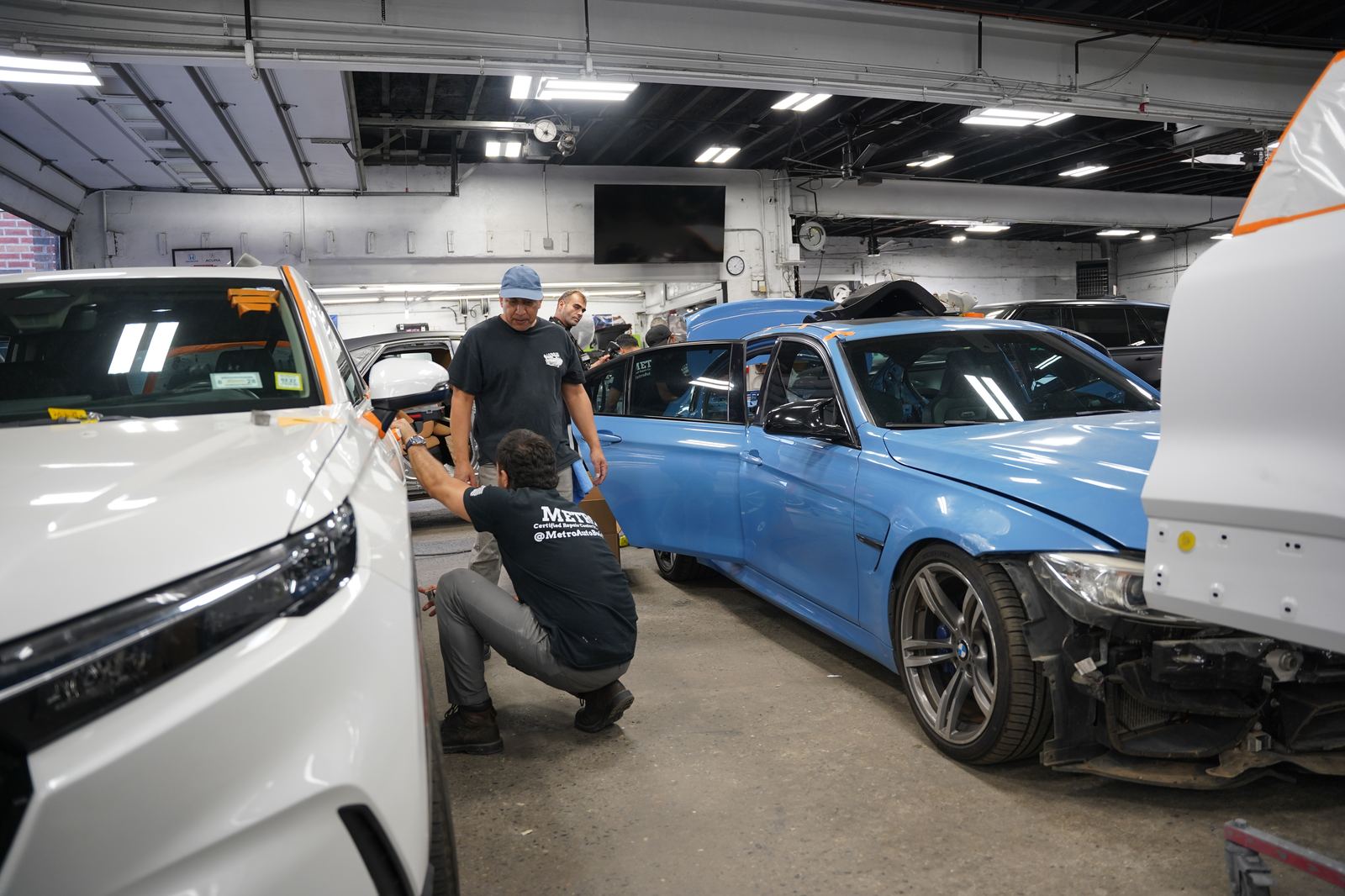 Metro Auto Body technicians assessing collision damage on a BMW M3