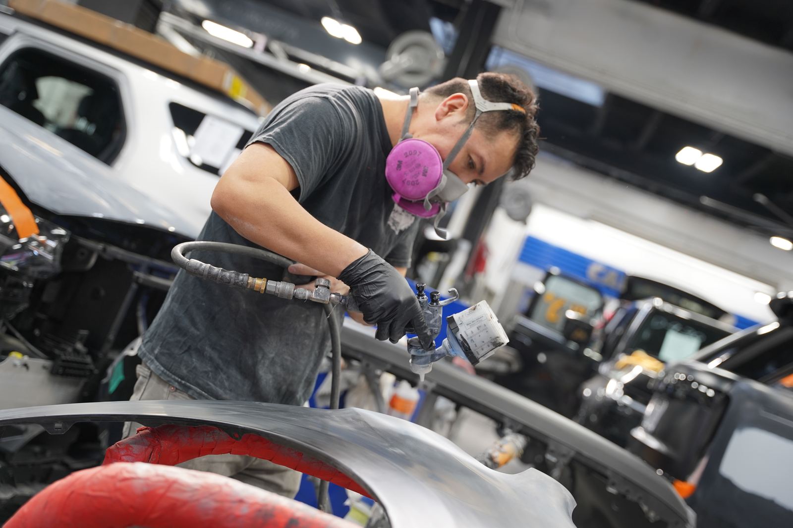 Metro Auto Body technician spray-priming a bumper in the paint department