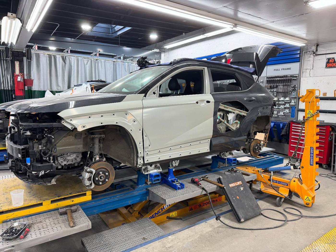 Vehicle on lift beside Car-O-Liner tool wall at Metro Auto Body